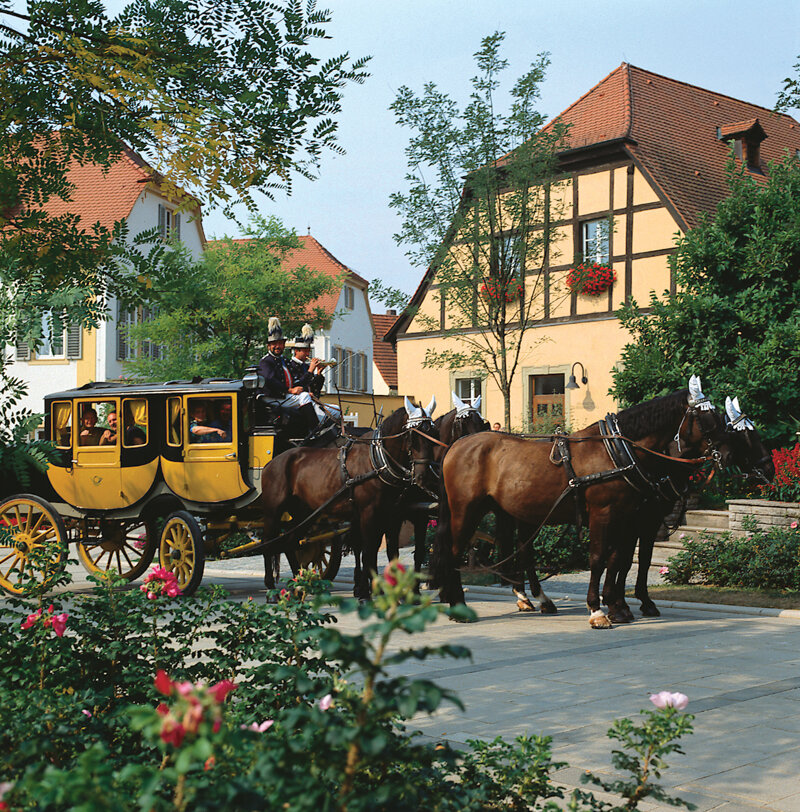 Kutsche mit Pferden vor einem Fachwerkhaus
