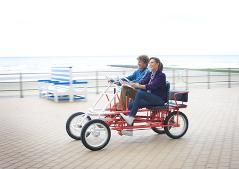 Paar auf Tretwagen auf der Strandpromenade