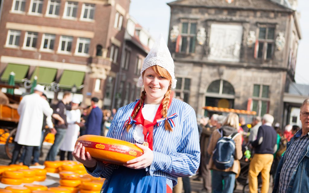 Mädchen in holländischer Tracht mit einem Gouda Käse