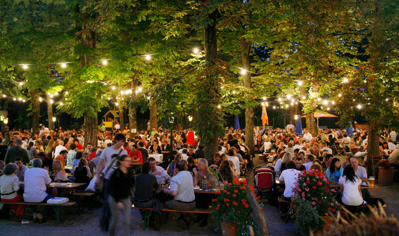 beleuchteter Biergarten bei Nacht mir vielen Besuchern