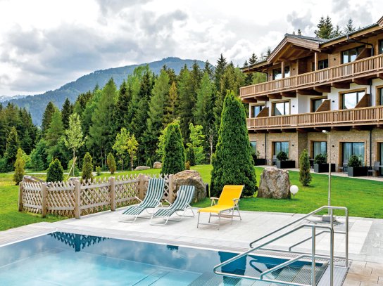 Außenpool mit Liegen hinter dem Hotel