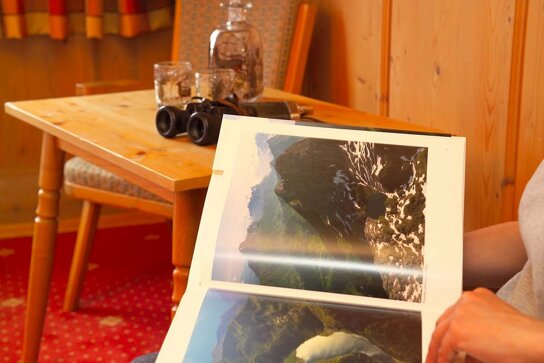 Gast blättert in einem Buch über Wandern in den Alpen