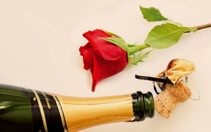 Offene Sektflasche mit einer Rose