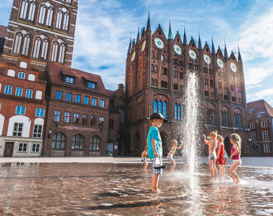 Spielende Kinder mit der Wasserfontäne auf dem Alten Markt vor dem Rathaus playing Children in front of the town hall c Erik Hart - Tourismuszentrale Stralsund