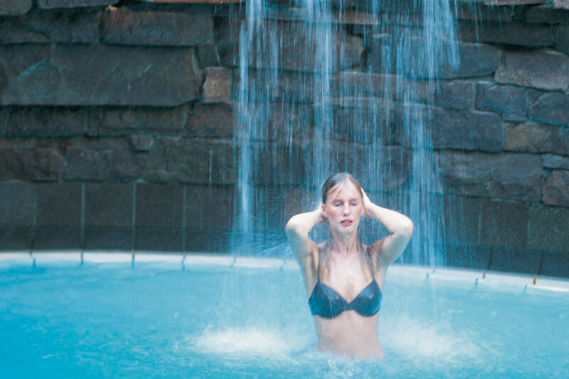 Frau unter Wasserfall in der Caracalla Therme Baden-Baden