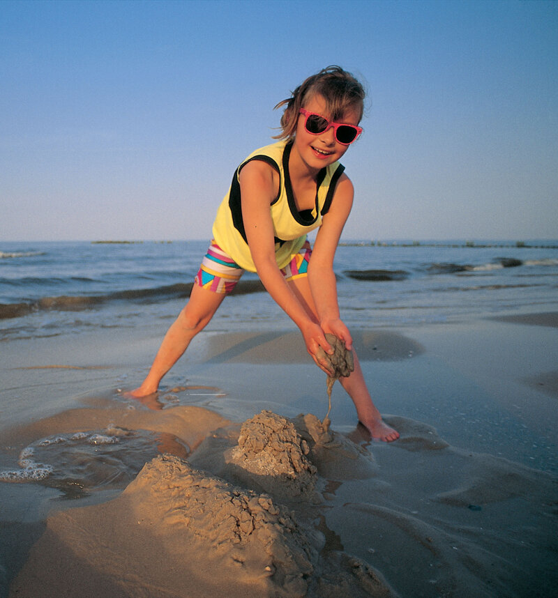 Kind baut Sandburg am Strand der Mecklenburgischen Ostseeküste – Familienurlaub an der Ostsee