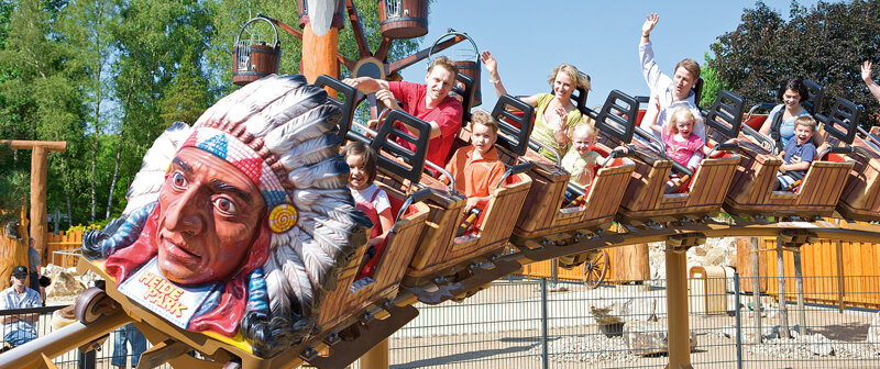 Freizeitpark mit Achterbahn und Familien in der Frühlingssaison