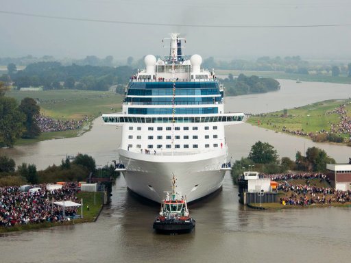 Kreuzfahrtschiff wir von einem kleinen Boot durch eine Flussenge gelotst.