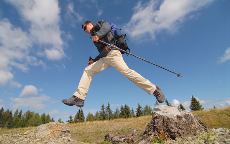 Wanderer springt über Bach