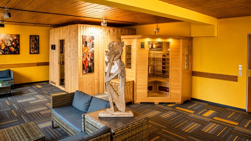warmer wellnessbereich mit holzsauna und skulptur
