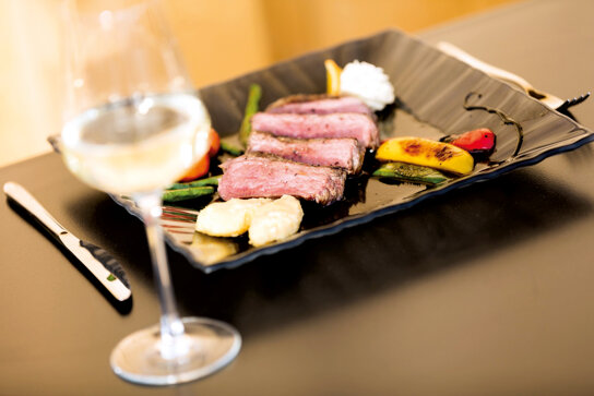 Teller mit angerichtetem Essen und ein Glas Wein