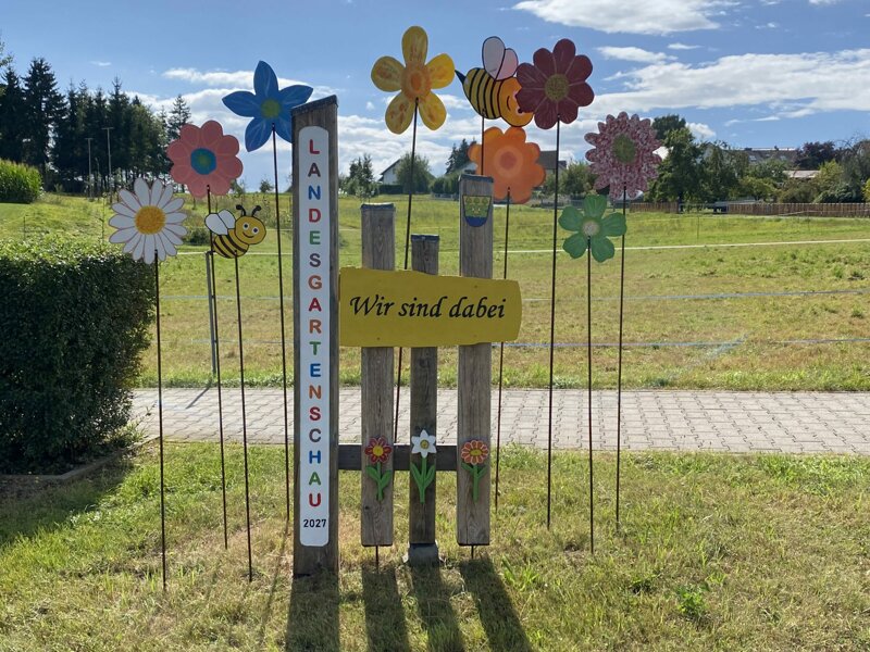 „Wir sind dabei“- Willkommensschild mit Holzblumen in Büdingen-Michelau. 