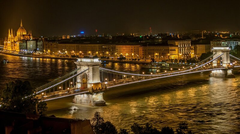 Széchenyi-Kettenbrücke Budapest bei Nacht – illuminierte Pylone spiegeln sich in der Donau
