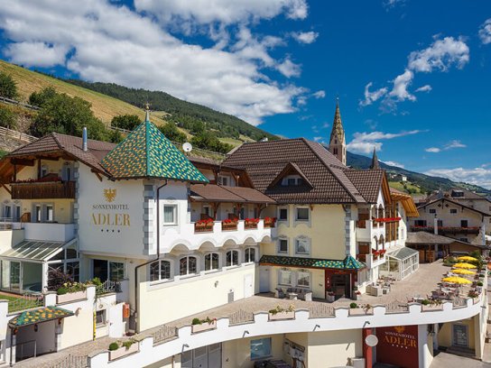 Außenaufnahme des Sonnenhotels Adler in Villanders mit Liegewiese und Terrasse
