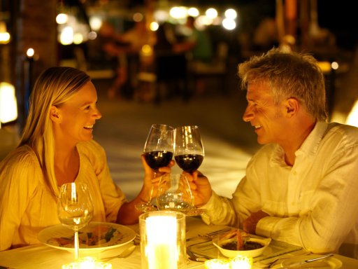 Paar stößt bei romantischem Abendessen in Kerzenschein bei einem Glas Wein an