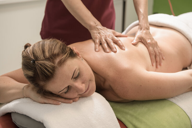 Eine Frau erhält eine Kosmetikanwendung von zwei Mitarbeiterinnen  