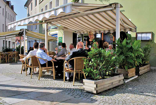 Menschen auf Terasse mit Sonnensegel