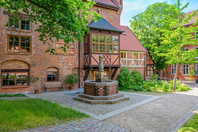 Brunnen vor Backsteinhaus