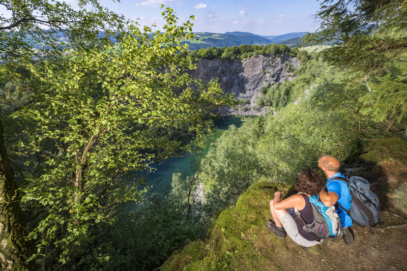 Paar sitzt auf einem Felsen über dem Wald