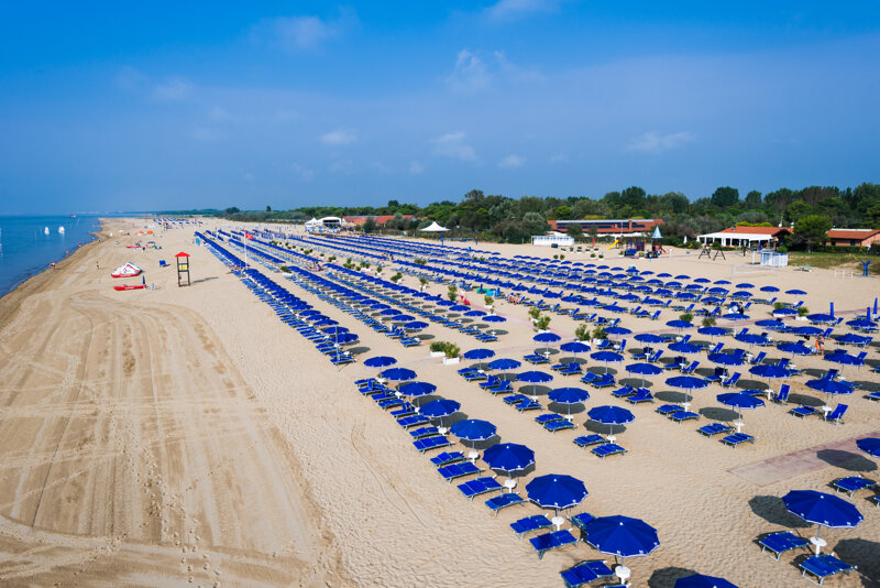 Strand mit Liege und Sonnenschirmen
